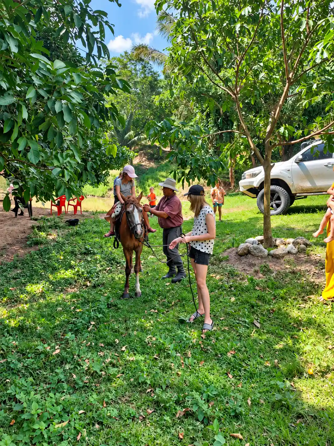 A child on horseback accompanied by adults in green surroundings